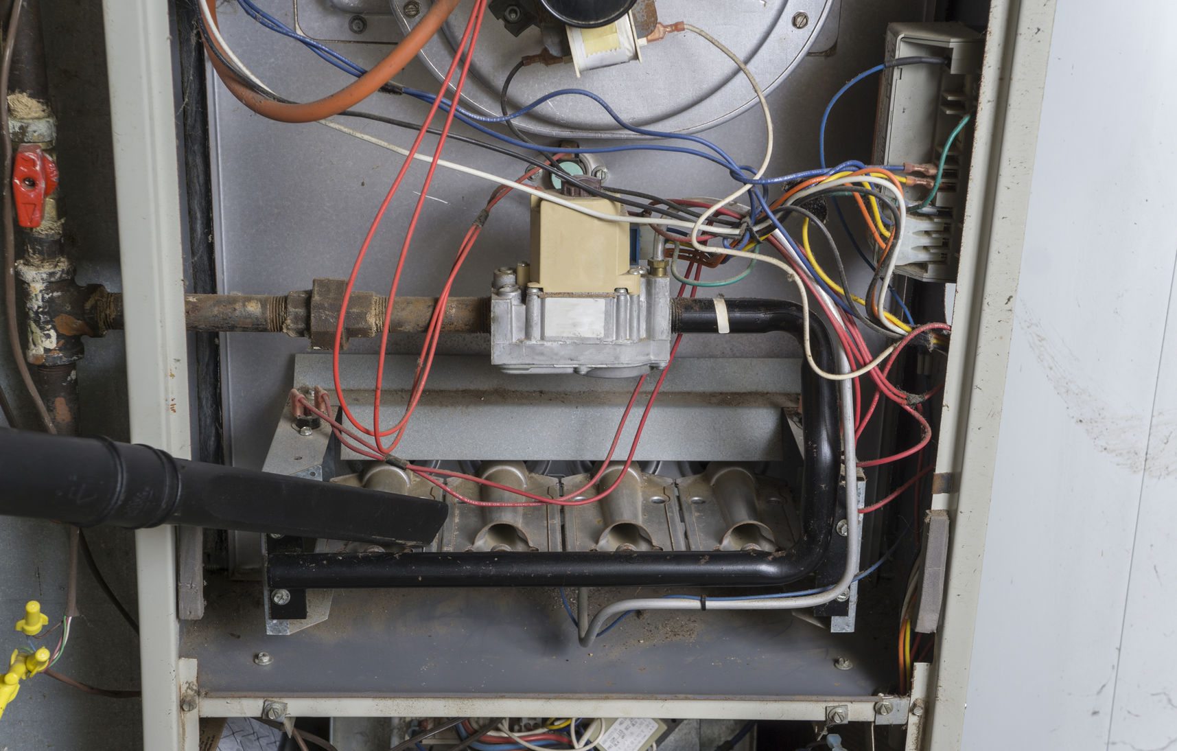 46562865 – repairman using a vacuum inside of a gas furnace.
